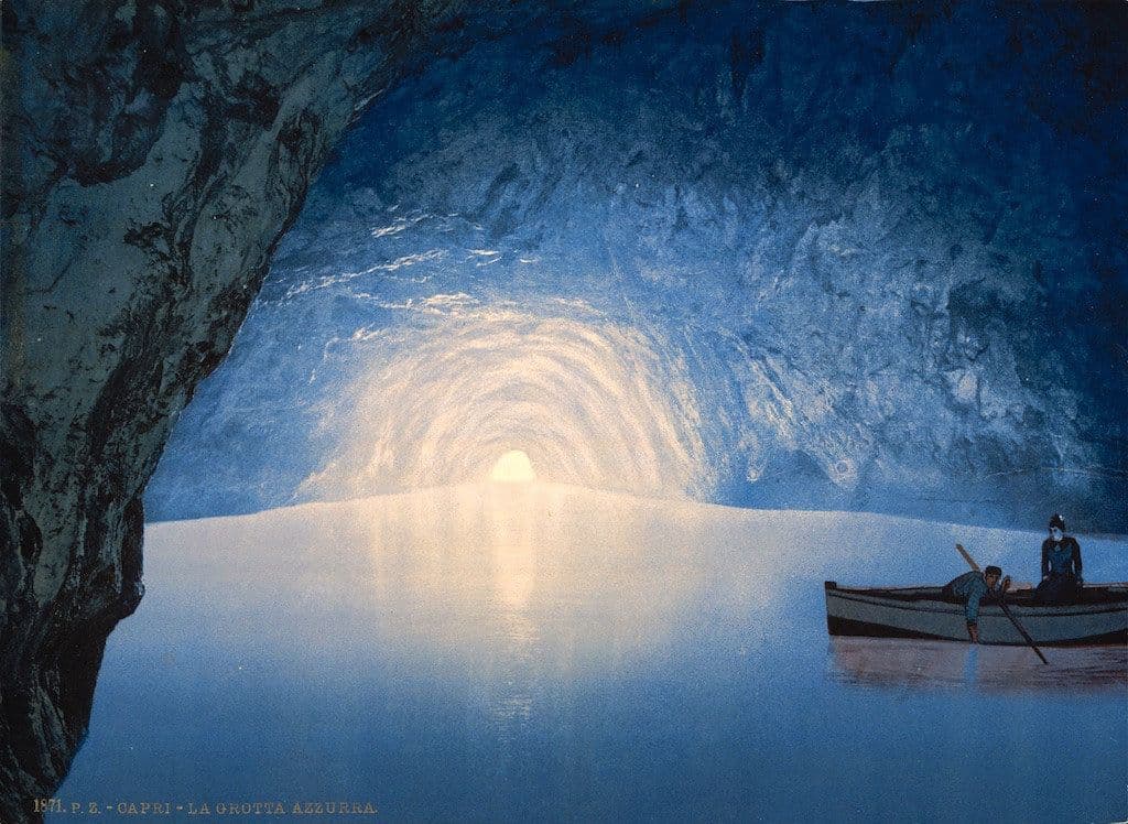 Vintage postcard of the Blue Grotto in Capri, Italy, showing a small rowboat with two figures inside a luminous blue sea cave.